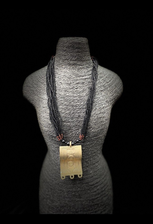 Collier ethnique africain composé de perles anciennes en pâte de verre et d’un pendentif décoratif en bronze. Une pièce originale pour les collectionneurs et amateurs d’art africain.